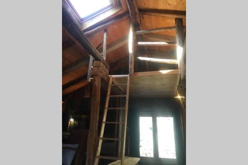 an attic with a ladder and a window in it at La cabane de l'homme tranquille in Le Trétien