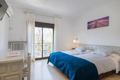 a white bedroom with a large bed and a window at Els Caçadors de Maçanet in Maçanet de Cabrenys