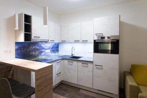 a kitchen with white cabinets and a sink and a counter at Aparthotel Tyrol in Lermoos