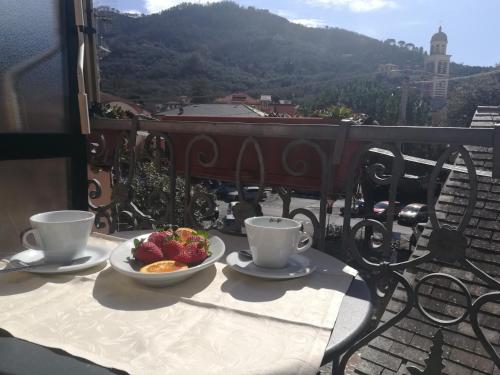 a table with two cups and a bowl of fruit on a balcony at affittacamere la loggia in Levanto