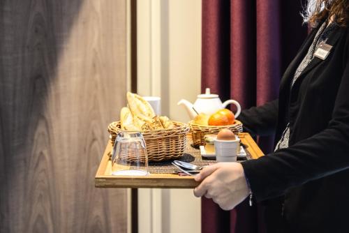 a woman holding a tray with a basket of food at Best Western Plus Paris Velizy in Vélizy-Villacoublay