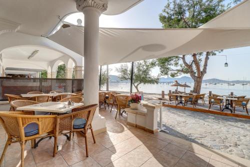 an outdoor restaurant with tables and chairs and a view of the water at Hoposa Bahia in Port de Pollensa