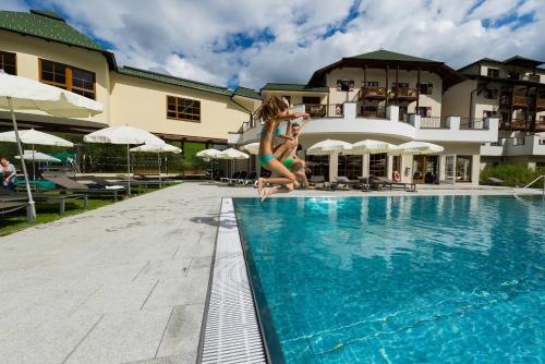 a young girl is jumping into a swimming pool at ROBINSON AMADÉ in Kleinarl