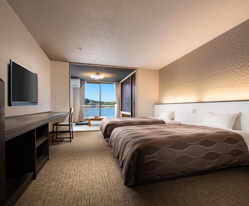 a hotel room with two beds and a flat screen tv at The Gran Resort Mikatagoko in Mihama