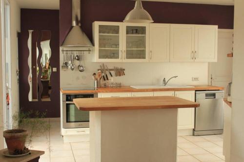 une cuisine avec des armoires blanches et un comptoir en bois dans l'établissement Jolie maison 2 chambres - jardin, à Le Hamel