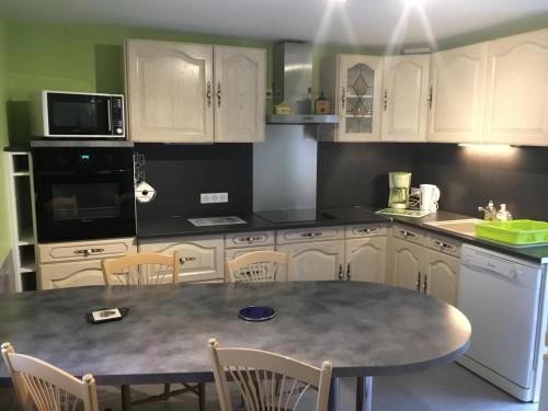 a kitchen with white cabinets and a table with chairs at Gîte Dubois in Romanswiller