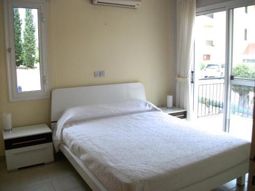 a bedroom with a white bed and a large window at Villa Laurel in Peyia