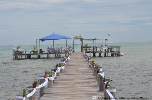 a wooden pier with chairs and an umbrella on the water at Boraha Village Ecolodge in Sainte Marie