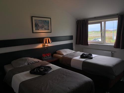 a hotel room with two beds and a window at Hotel Dijkzicht in Oudeschip