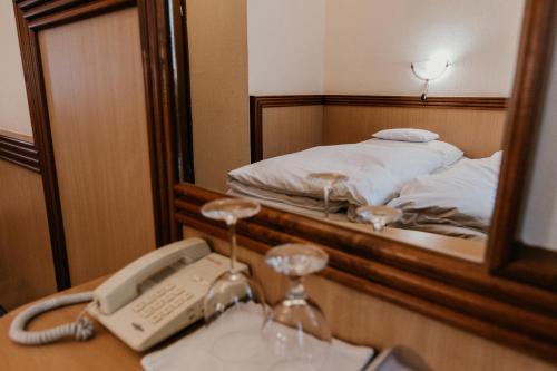 a phone on a desk in front of a bed at Tisza Hotel in Szeged