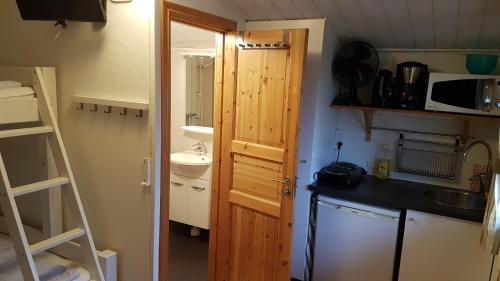 a small kitchen with a sink and a wooden door at Korskullens Stugor in Söderköping