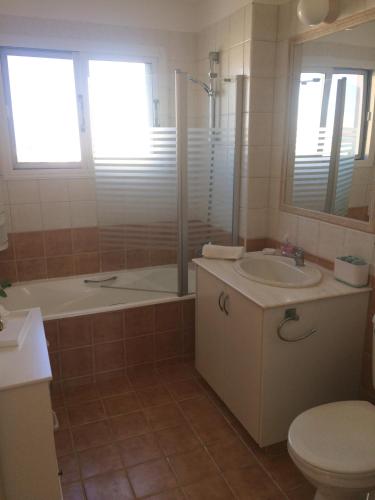 a bathroom with a tub and a sink and a toilet at Villa Laurel in Peyia