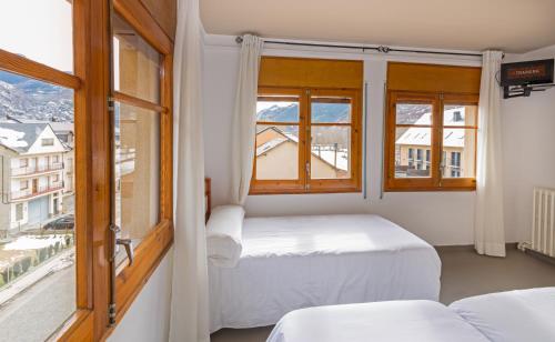 a bedroom with two beds and a large window at Hostal Trainera in Esterri d'Àneu