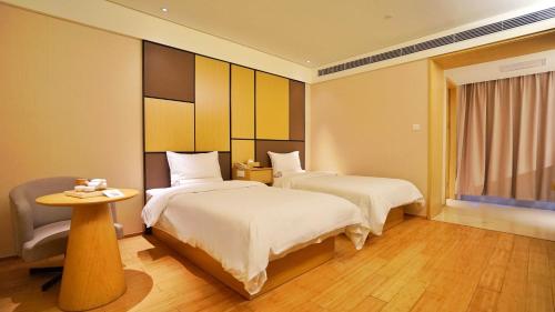 a hotel room with two beds and a table at Hanting Youjia Hotel (Dali Erhai Park) in Dali