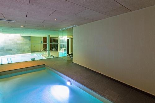 a swimming pool in a room with a tub and a bathroom at Hostal Trainera in Esterri d'Àneu
