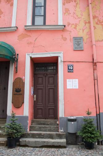 a pink building with a brown door and stairs at Amber Private Rooms in Rīga