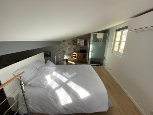 un grand lit blanc dans une chambre avec une fenêtre dans l'établissement Le Loft Saint Rémi, à Bordeaux