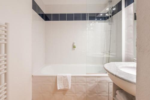 uma casa de banho branca com um chuveiro e um lavatório. em Residhotel Grenette em Grenoble