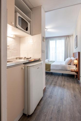 a kitchen and a bedroom with a bed in a room at Residhotel Grenette in Grenoble