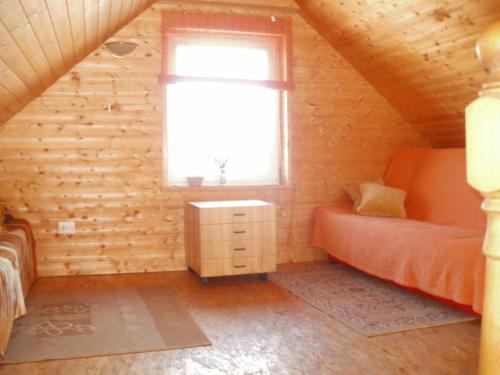 a bedroom in a log cabin with a bed and a window at Talsu Pirtiņa Vijoles in Talsi