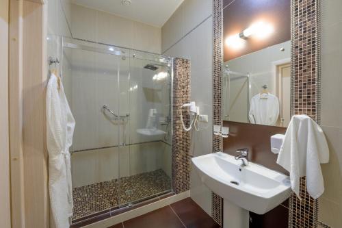 uma casa de banho com um chuveiro, um lavatório e um chuveiro em Hotel Aquamarin em Surgut