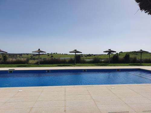 una piscina con sombrillas de fondo en Hotel Rural Santo Antonio en Arronches