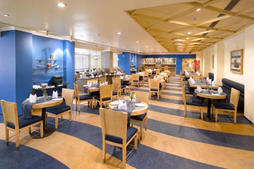 a restaurant with blue walls and tables and chairs at Peerless Hotel Durgapur in Durgāpur
