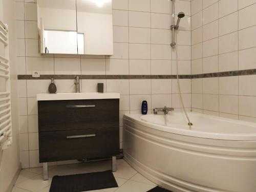 une salle de bain avec une baignoire, un lavabo et un miroir dans l'établissement Maison Cheptainville AVEC TERRASSE SUR VERDURE, à Cheptainville