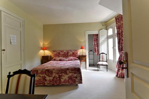 um quarto com uma cama, uma cadeira e janelas em Château Maucaillou em Moulis-en-Médoc
