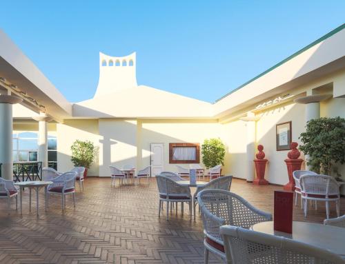 a patio with chairs and tables and a screen at Dom Pedro Garajau in Caniço