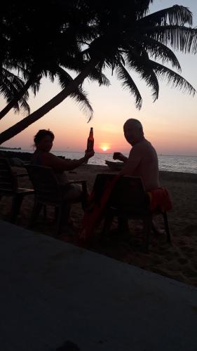 dos personas sentadas en la playa viendo la puesta de sol en Anicia Beach House, en Negombo