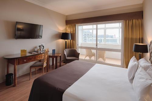 Cette chambre comprend un lit, un bureau et une fenêtre. dans l'établissement Golden Tulip Porto Gaia Hotel, à Vila Nova de Gaia