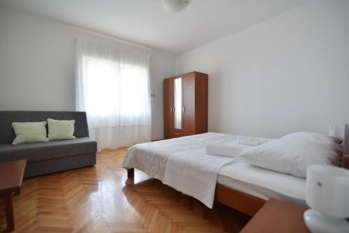 ein weißes Schlafzimmer mit einem Bett und einem Sofa in der Unterkunft Apartmani Badurina - Maslina in Lun