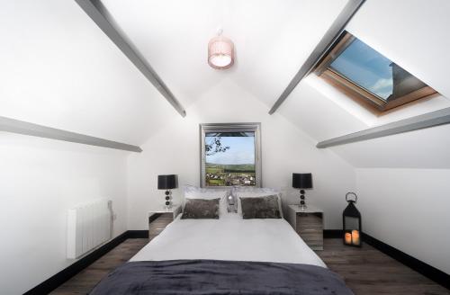 a bedroom with a bed with white walls and windows at Curragh House Lodges in Kinsale