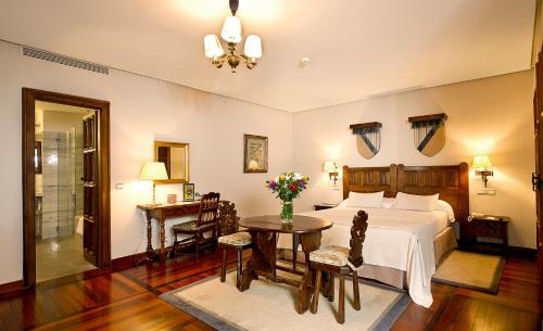a room with a bed, table, chairs and a lamp at Parador de Santiago - Hostal Reis Catolicos in Santiago de Compostela