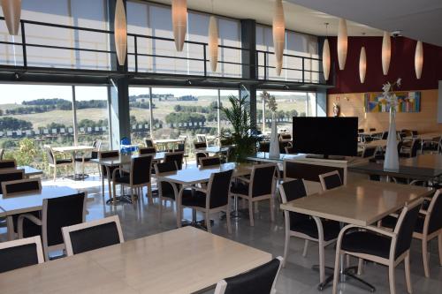 a restaurant with tables and chairs and large windows at Hotel Holiday Inn Express Madrid-Rivas by IHG in Rivas-Vaciamadrid
