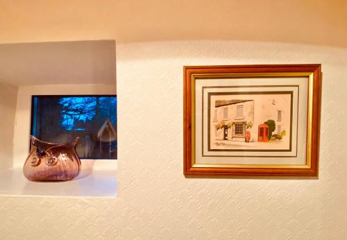 a picture on a wall with a vase on a shelf at Hawkshead Cottage in Glossop