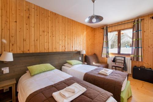 two beds in a room with wooden walls at Loges du Jura in Cerniébaud