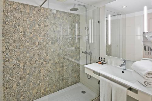 uma casa de banho com um chuveiro e um lavatório. em Golden Tulip Porto Gaia Hotel em Vila Nova de Gaia