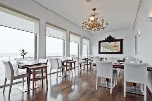 a dining room with tables and white chairs and a chandelier at Golden Tulip Porto Gaia in Vila Nova de Gaia