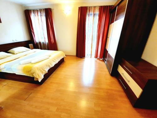 a bedroom with a large bed and red curtains at GrandVille Apartments in Bucharest