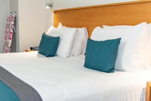 a bed with white pillows and blue pillows at Kingscliff, BW Signature Collection in Clacton-on-Sea