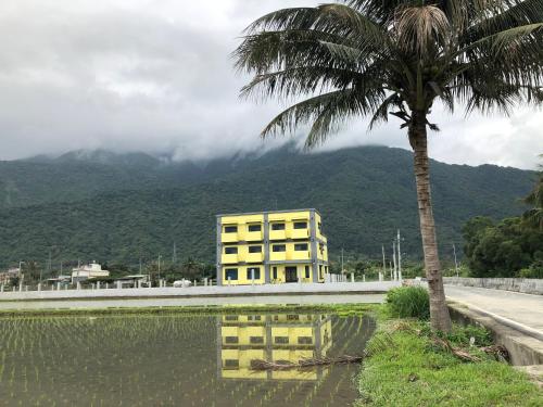 a yellow building next to a palm tree and a road at 太魯閣惠宇民宿 in Xincheng