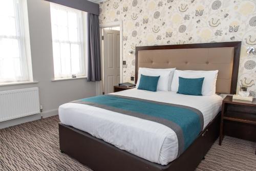 a hotel room with a large bed with blue pillows at Kingscliff, BW Signature Collection in Clacton-on-Sea
