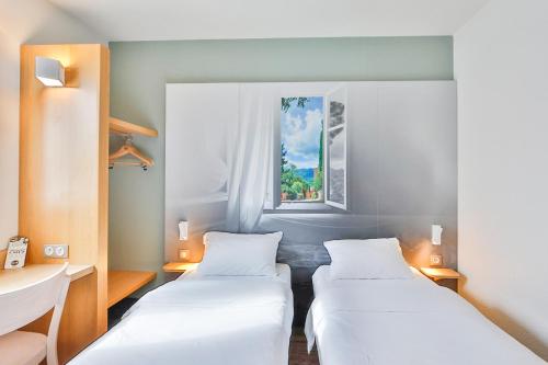 2 camas en una habitación con ventana en B&B HOTEL Valence Sud en Valence