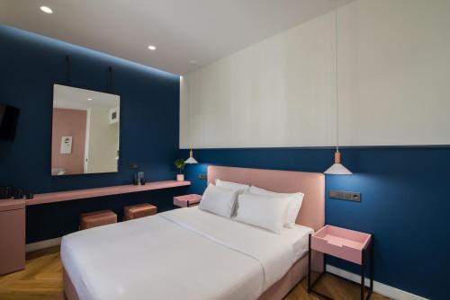 a bedroom with a white bed and a blue wall at Ederlezi Zoubourlou Aparthotel in Athens
