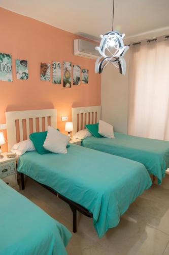 two beds in a room with blue sheets at Pension Internacional in Córdoba