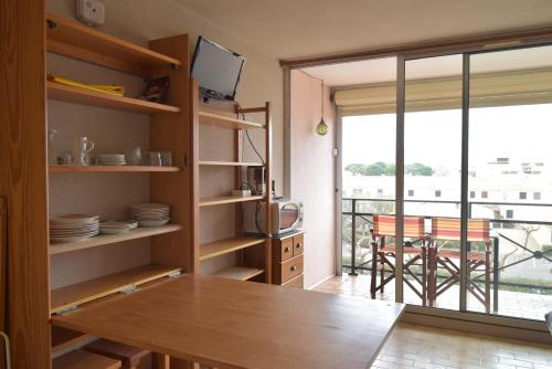 uma cozinha com uma mesa e vista para uma varanda em Studio cabine résidence avec piscine et garage le Lagon bleu em Le Grau-du-Roi