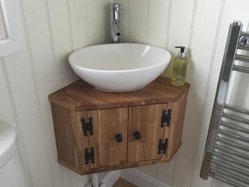 a bathroom with a bowl sink on a wooden stand at Weatherhead Farm Shepherds Hut in Buckingham