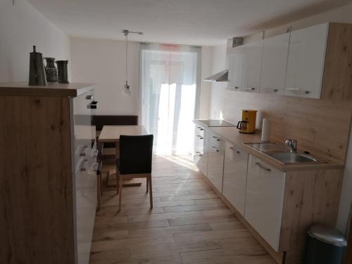 Una cocina con gabinetes blancos y una mesa y una silla. en FW Knöppel Sonja und Stefan, en Zapfendorf